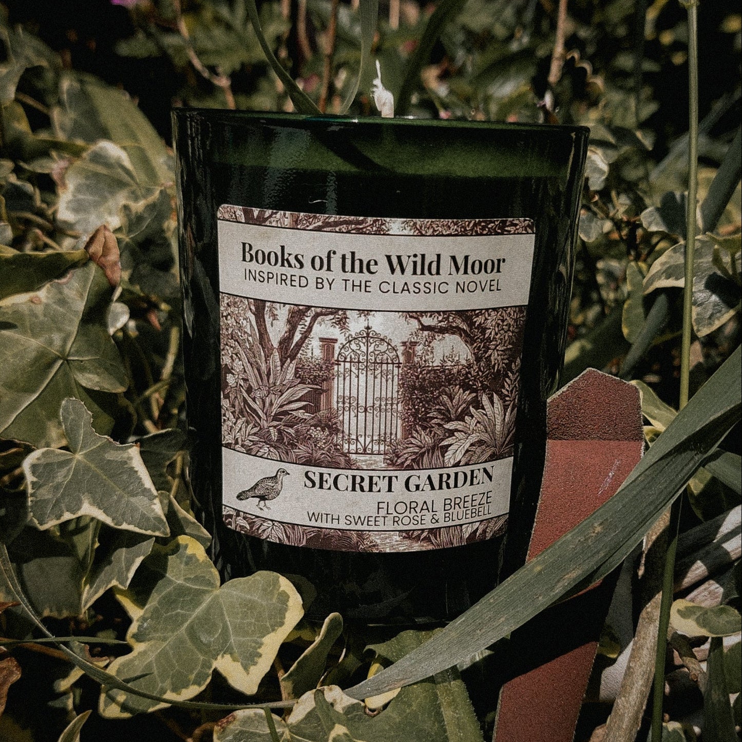 Secret Garden Candle surrounded by greenery