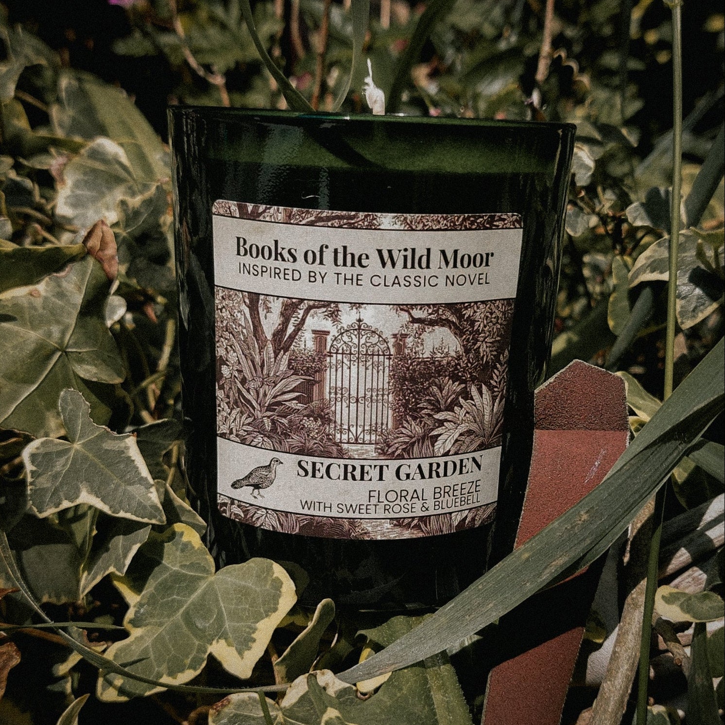 Secret Garden Candle surrounded by greenery